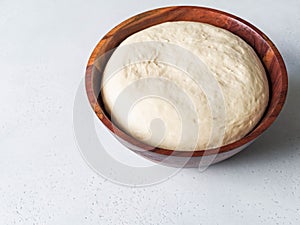 Wheat flour yeast dough in wooden bowl. Copy space