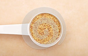 Wheat germs in measuring spoon on brown background