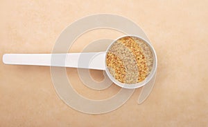 Wheat germs in measuring spoon on brown background