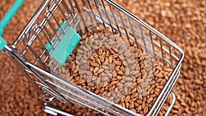 Wheat grains falling into a mini supermarket cart in slow motion close-up.