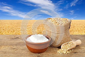 Wheat grains and flour on field background
