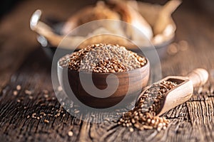 Wheat grains-the main ingredient of the bread filled in wooden bowl and wooden rustic scoop. Bakend crusty bread in the backround