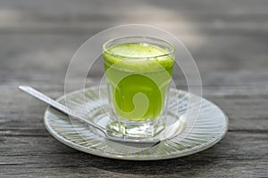 Wheat grass juice natural drink with fresh wheatgrass in glass on old wooden table background. Organic healthy organic green detox