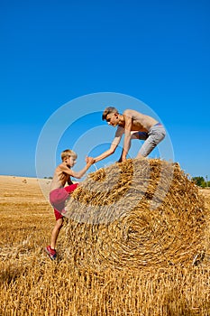 Wheat hay on an agricultural field. Two brothers are fooling around and laughing. Children`s day in nature. Rural children on
