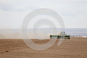 A farmer in a field, planting wheat.