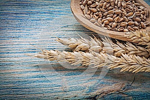 Wheat rye ears grains wooden spoon on wood board
