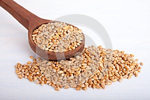 Wheat seeds in big wooden spoon on white background, perspective view