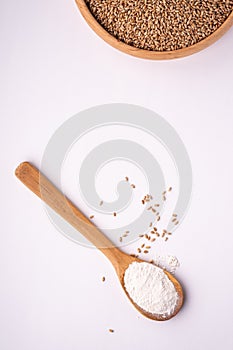Wheat seeds grains in wooden bowl near with flour in spoon spatula with heap of grains, top view, flat lay