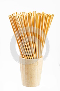 Wheat straw for drinking water in wooden glass on white background