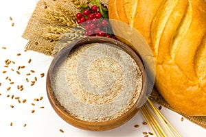 Wheat whole grain flour in ceramic bowl, wheat ears and homemade bread