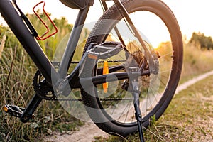 The wheel of bicycle that stands on a country road at sunset, a break in a bike ride