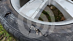 A wheel from a car with a damaged tire, worn out due to prolonged use, numerous damage.