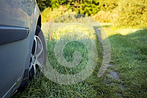 The wheel of car on ground with grass on countryside. car is on nature close-up. tourist trip by car