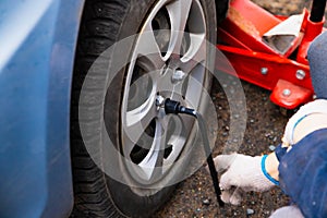 Wheel change, car is jacked up. Male hands unscrews wheel washers by ball wrench