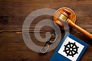 Wheel of dharma - Buddhist symbol - near gavel and book on wooden table. Religious conflict concept. Copy space