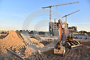 Wheel excavator during road work at construction site. Screeding gravel for laying asphalt and installing borders and curbs on