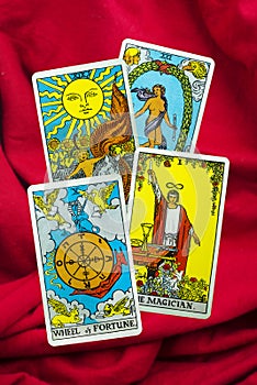 Wheel of Fortune, The Magician, The Sun, The World, Tarot Card of Rider Waite deck on red fabric background.
