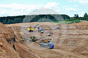 Wheel front-end loader loads sand into a dump truck. Heavy machinery in the mining quarry, excavators and trucks.