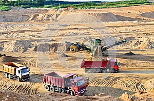 Wheel front-end loader loads sand into a dump truck. Heavy machinery in the mining quarry, excavators and trucks. Mobile jaw