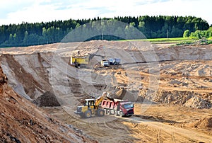 Wheel front-end loader loads sand into a dump truck. Heavy machinery in the mining quarry, excavators and trucks. Mobile jaw