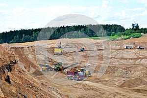 Wheel front-end loader loads sand into a dump truck. Heavy machinery in the mining quarry, excavators and trucks. Mobile jaw