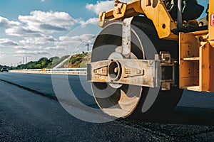 Wheel of large road roller compacts fresh asphalt, construction photo