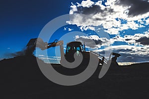 Wheel loader excavator with field background during earthmoving work, construction building