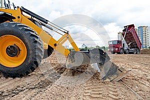 Wheel loader excavator machine wih multi-purpose bucket levelling construction site during earthmoving works