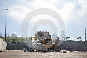 Wheel loader with lifted scrap grapple moving along a recycling center