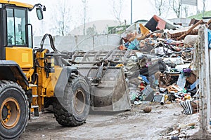Wheel loader with lifted scrap grapple moving along a recycling center