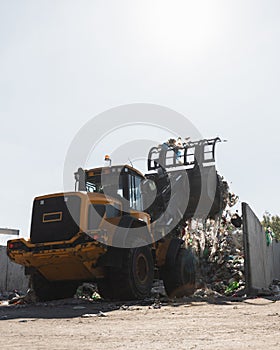 Wheel loader with lifted scrap grapple moving along a recycling center