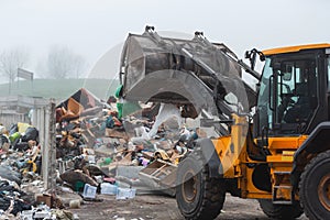 Wheel loader with lifted scrap grapple moving along a recycling center