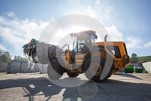 Wheel loader with lifted scrap grapple moving along a recycling center