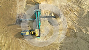 Wheel loader load sand in dump truck in open pit. Heavy machinery on developing opencast. Front end loader on earthworks in quarry