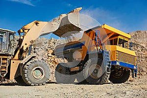 Wheel loader loading ore into dump truck at opencast