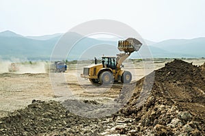 Wheel loader loads clay into the bucket of a dump truck