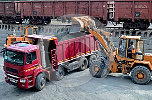 Wheel loader loads gravel into a dump truck at a cargo railway station. Fron-end loader unloads crushed stone in a gravel pit.