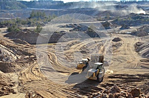 Wheel loader loads sand into heavy mining dump truck at the opencast mining quarry. Heavy machinery in the open pit, excavators,
