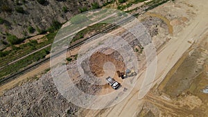 Wheel loader loads stones into a dump truck. Aerial view of open pit development. Heavy machinery working in quarry