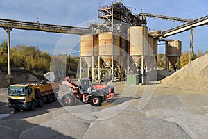 Wheel loader loads truck with gravel in a sand pit - transport and mining of building materials for the construction industry
