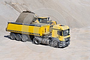 Wheel loader loads a truck with sand in a gravel pit