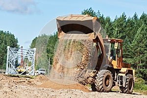 Wheel loader machine unloading sand at eathmoving works at construction site