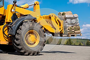 Wheel loader moving cargo green grass lawn rolls