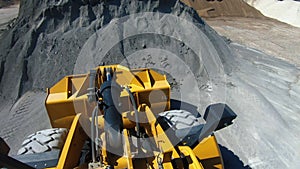 Wheel loader picks up into bucket crushed stone and moves