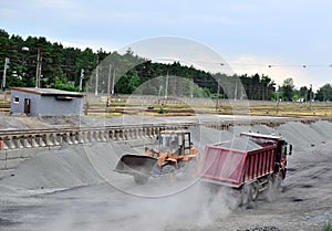 Wheel loader unload gravel and crushed stone in the dump truck. Unloading bulk cargo with of the cargo railway platform