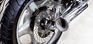Wheel and muffler sports bike close-up in garage.