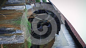 Wheel of old water mill. Wooden wheel spinning under stream of water. Old barn mill with paddle wheel. Old wooden wheel from mill