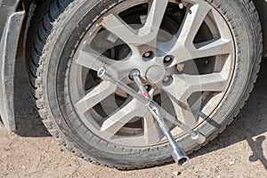 Wheel replacement on the road by the driver. Replacing summer tires with winter tires with a handy wrench by a mechanic