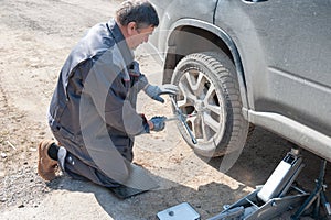 Wheel replacement on the road by the driver. Replacing summer tires with winter tires with a handy wrench by a mechanic