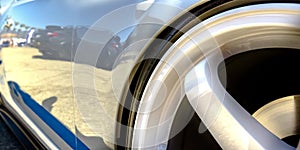 Wheel rim of a shiny white car with blue decal